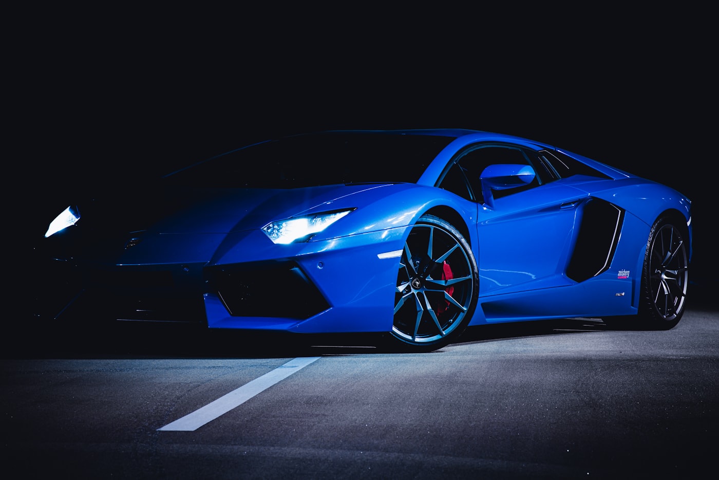A blue exotic supercar lit against a dark background